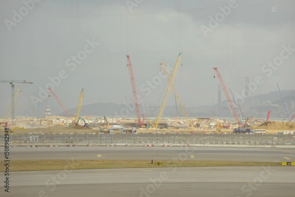 Fototapeta Construction site in Tung Chung, Hong Kong. Cranes truck working in construction site. Construction background, construction equipment crane background.