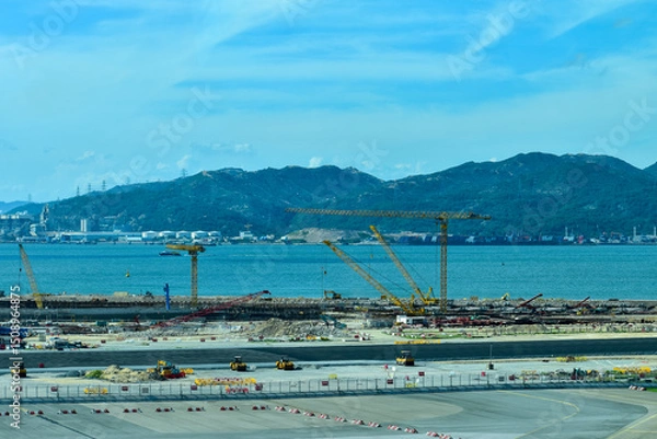 Fototapeta Construction site in Tung Chung, Hong Kong. Cranes truck working in construction site. Construction background, construction equipment crane background.