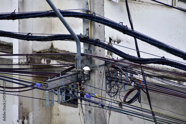 Fototapeta Close-up of messy electric cables on pole in Thailand. Entangled wires on an Electricity Pole. 