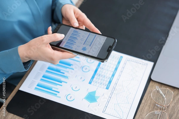 Fototapeta Woman taking photo of document using scanning app on smartphone at desk in office, closeup