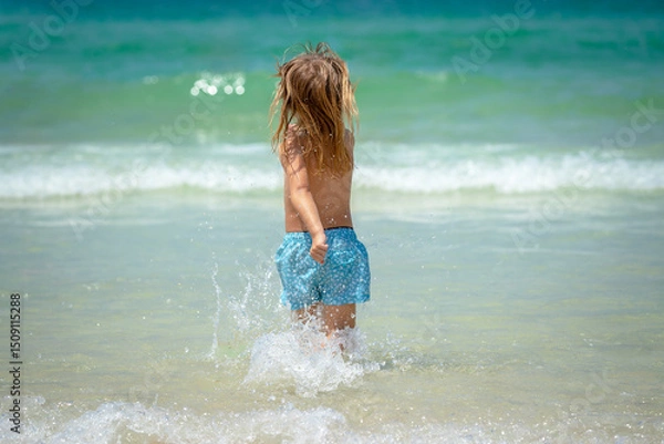 Obraz Joyful child is playing in the waves on a beautiful sunny beach