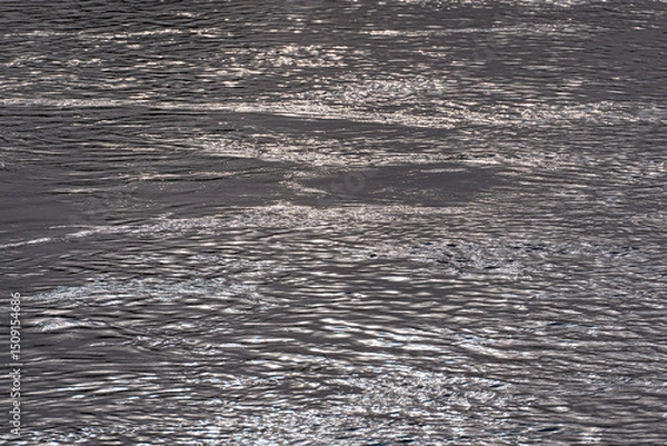 Fototapeta Full frame of dark wavy water with whirlpools, lead-colored water surface with ripples and reflection of texture surface, shimmering water, natural texture, abstract water surface.