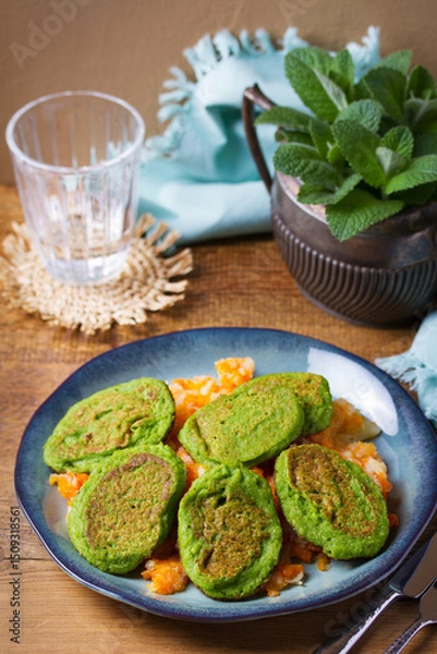 Fototapeta Green pea cakes on mashed carrot and parsnip. Vegetable fritters, pancakes on blue plate
