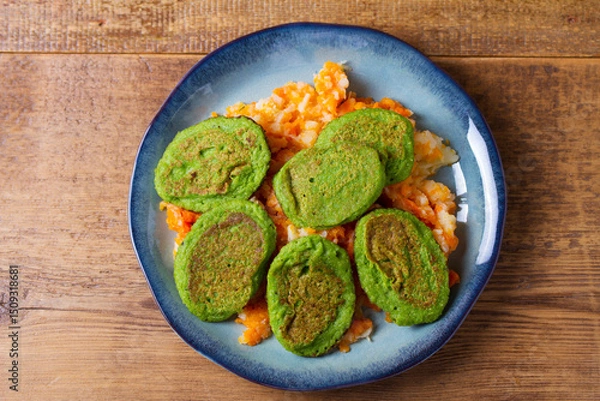 Fototapeta Green pea cakes on mashed carrot and parsnip. Vegetable fritters, pancakes. View from above, top studio shot