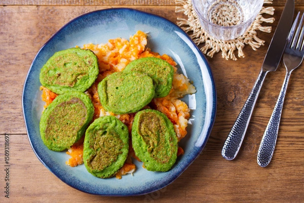 Fototapeta Green pea cakes on mashed carrot and parsnip. Vegetable fritters, pancakes. View from above, top studio shot