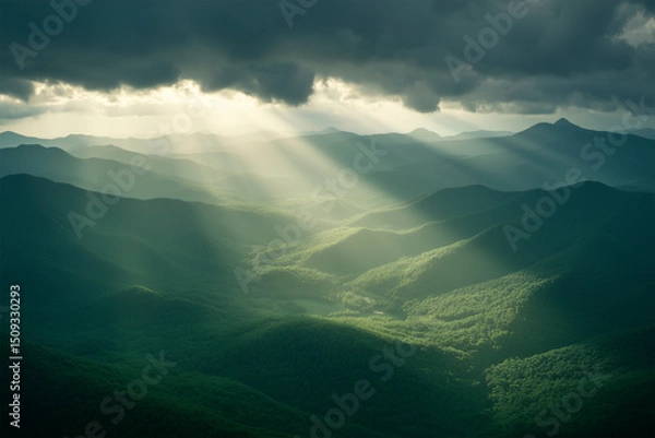 Fototapeta light beams clouds through clouds illuminating mountains in a valley
