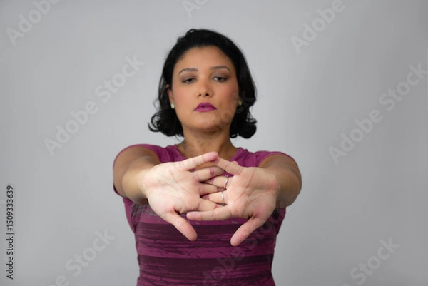 Fototapeta Beautiful and serious woman stretching her arms forward. Ideal for home workout, exercising, warm-up and physiotherapy. Neutral gray background with copy space. Focus on foreground.