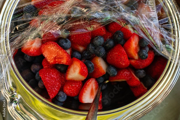 Obraz Strawberries and Blueberries in a bowl with plastic wrap on top 