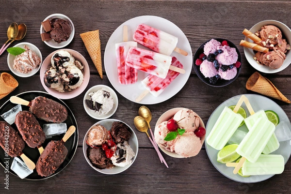 Obraz Cool summer food table scene. Variety of ice cream bowls, popsicles and frozen treats. Top view on a dark wood background.