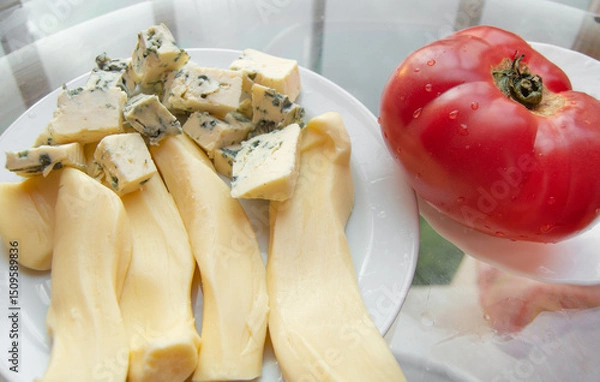 Fototapeta Different kinds of cheese on the plate and one red tomato, appetizers