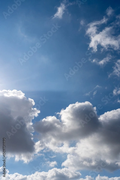 Obraz Soft white clouds float across a clear blue sky on a sunny day. A peaceful, minimal composition capturing the calm beauty of a fair weather afternoon.