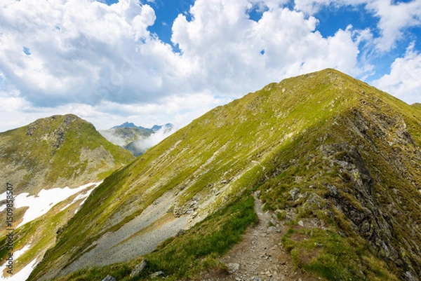 Fototapeta steep slopes of faragas mountain ridge in summer. hiking trail path through wonderful transylvania alps. blue sky with fluffy clouds