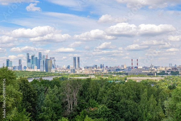 Fototapeta Scenic view from Vorobyovy Gory over Moscow River, lush green trees, and clouds in the blue sky. The natural beauty of Moscow River complements the city skyline in the background