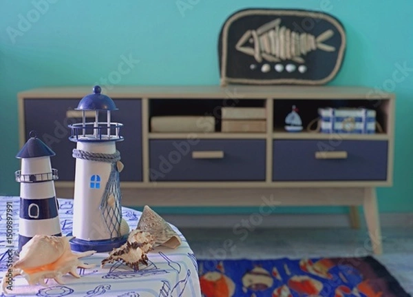 Fototapeta Lighthouses and shells on a table in a room decorated in a nautical style