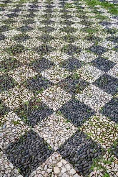 Fototapeta Traditional Portuguese Cobblestone Pavement With Black And White Stone Pattern. Calcada Portuguesa Mosaic Design, Historic Street Paving, Geometric Square Pattern
