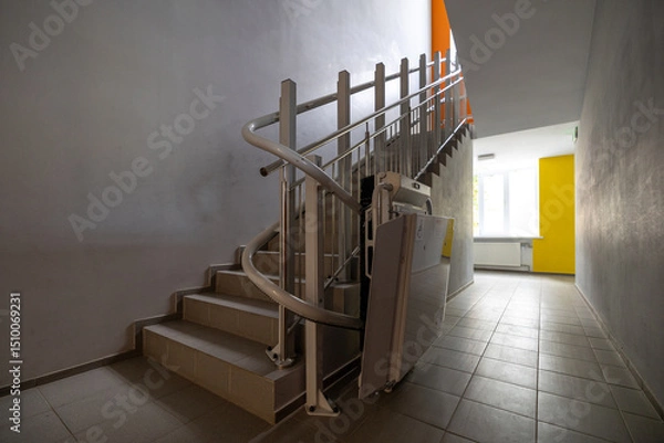 Fototapeta A modern staircase in a building interior features a stairlift for people with limited mobility, also known as reduced mobility, experience difficulty in moving around independently