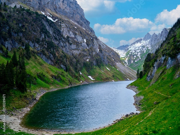 Fototapeta Scenic mountain landscape with a tranquil lake surrounded by lush greenery and snow-capped peaks