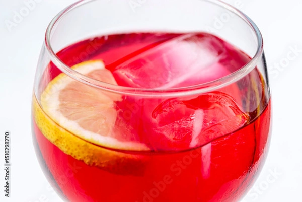 Fototapeta Close-up view of red aperitif drink with ice and lemon in a glass on white background
