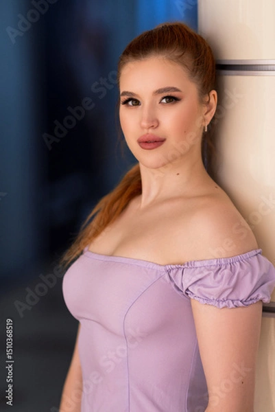 Fototapeta Elegant female model in lavender dress leaning against a light structure, with a composed expression and softly highlighted makeup