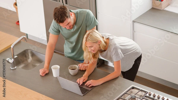Obraz Overhead View Of Couple Looking At Laptop In Modern Kitchen
