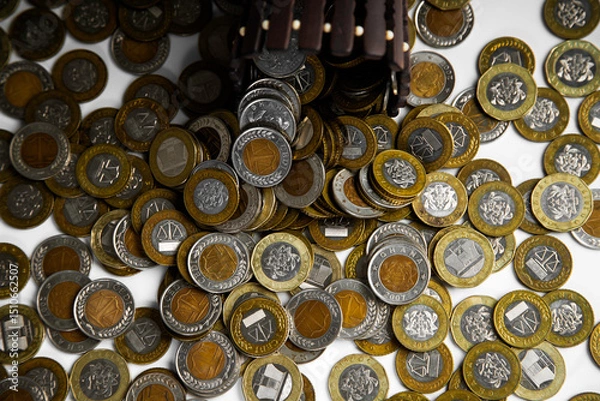 Obraz Ghanaian cedi coins in container poured spread on desk surface