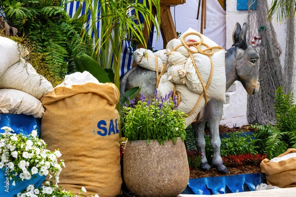 Fototapeta A scene with a life-size donkey figure loaded with white sacks of salt emphasises the historical importance of the salt trade in the Arucas region during the ‘Piedra y Flor’ festival