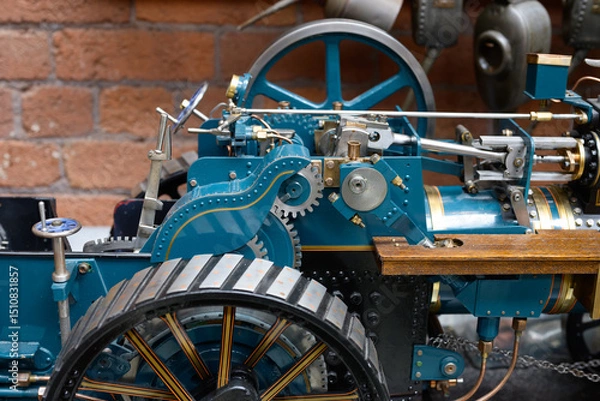 Fototapeta Vintage mechanical steam engine with visible gears and levers against a brick wall.