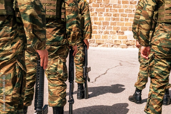Obraz Soldiers wearing camouflage pattern uniforms standing, carrying rifles, rear view