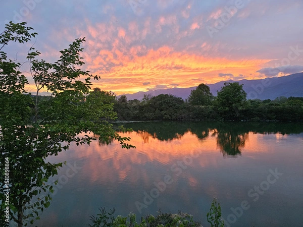 Fototapeta Beautiful sunset reflection over a calm lake surrounded by trees in Lake Kerkini National Park