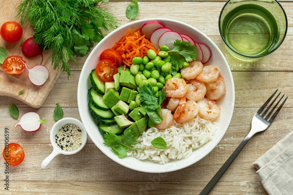 Fototapeta lunch bowl with rice, shrimps, avocado, cucumber, edamame beans radish and tomato in white bowl