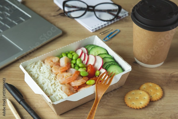 Fototapeta lunch break.Rice with shrimps and vegetables in paper take away box on desk