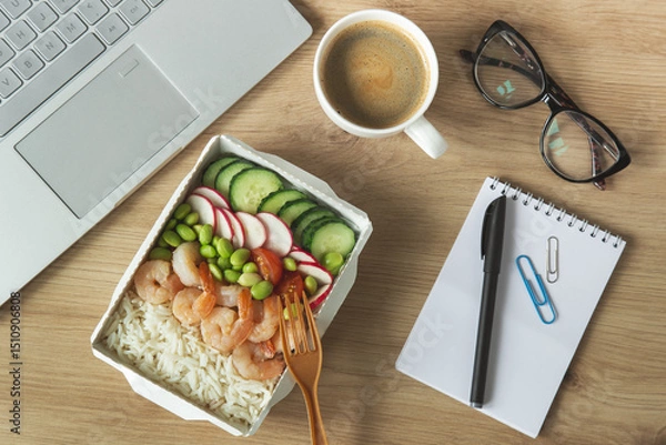 Fototapeta Lunch time. Rice with shrimps and vegetables in paper take away box on desk