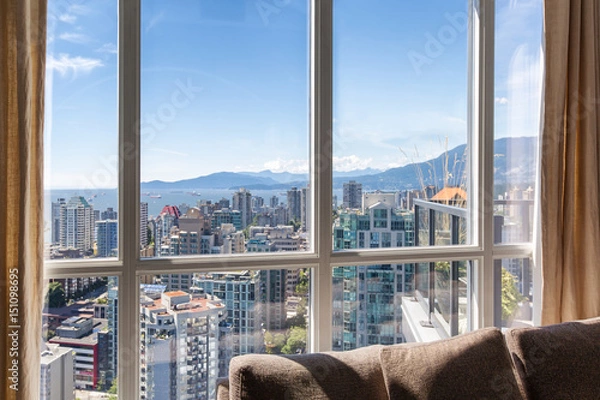 Obraz Vancouver, Canada. Penthouse window views of downtown Vancouver skyscrapers, bay and mountains on a sunny day with blue sky. Linen drapes and sofa cushions seen inside.