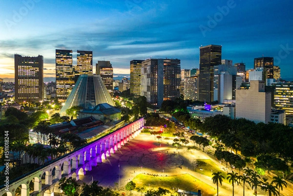 Fototapeta Lapa Aqueduct Illuminated With Purple and Pink Colors in the Evening With Tall Office Buildings of Rio de Janeiro Downtown