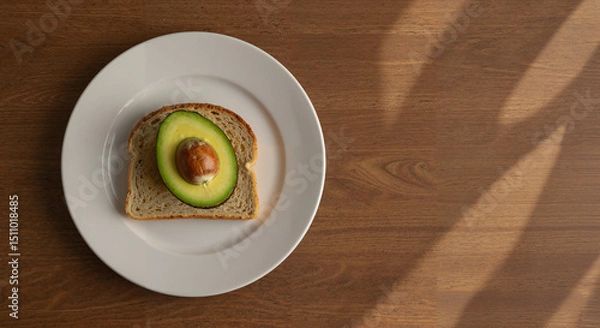 Fototapeta Avocado on whole grain toast served on a white plate against wood  