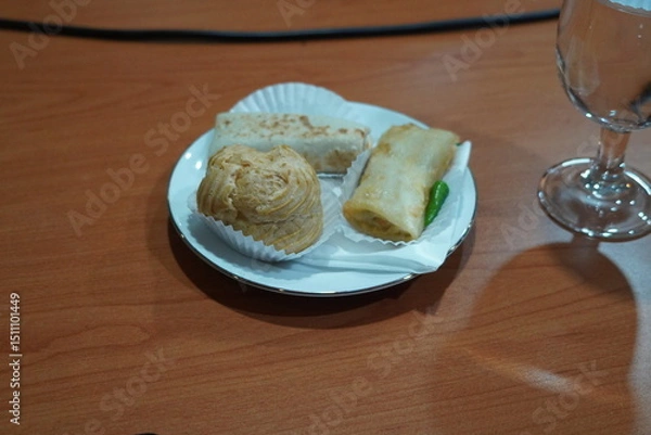 Fototapeta Assorted Indonesian pastries on a plate, with a glass of water