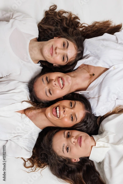 Fototapeta Group portrait of four young women smiling happily while lying together in a creative and harmonious arrangement