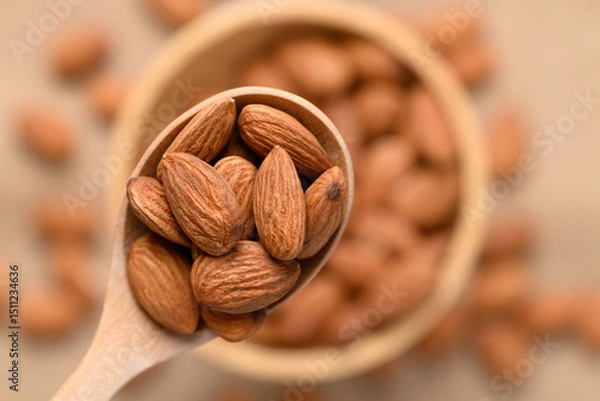 Obraz Raw almond nut seed in wooden spoon and bowl, Top view