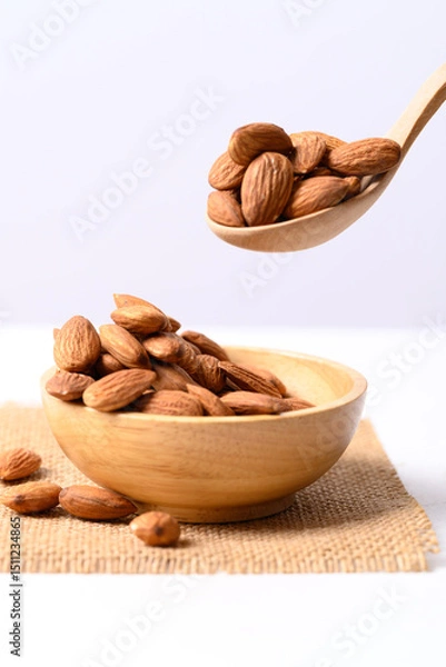 Obraz Raw almond nut seed in wooden bowl and spoon on white background