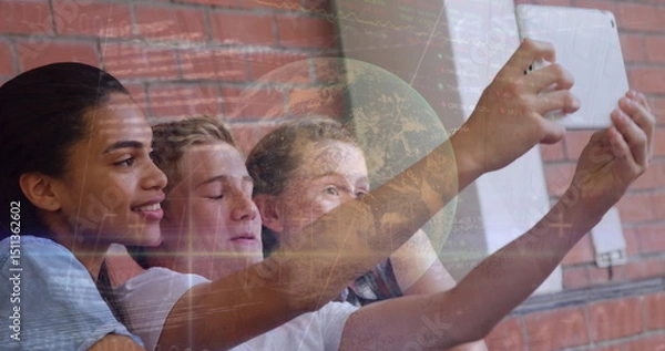 Obraz Image of financial graph and globe over happy diverse pupils taking selfie at school