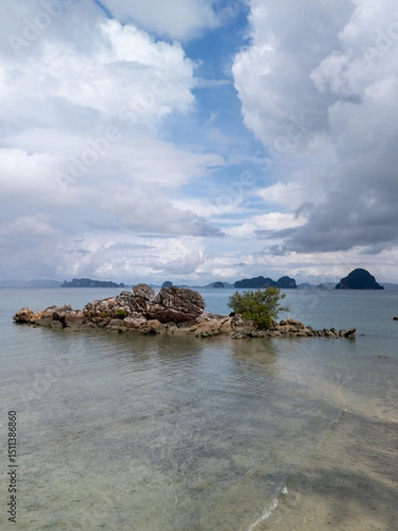 Fototapeta Portrait Drone Aerial View of rock island in turquoise sea under cloudy day 