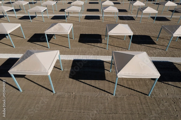 Obraz Perfect geometry of shadows and umbrellas on a deserted beach seen from above