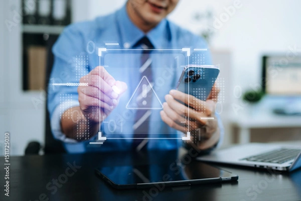 Fototapeta Businessman holding smartphone with digital alert icon. Concept of cyber risk, security warning, data protection, and tech threats