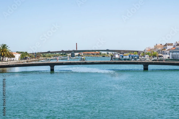 Fototapeta Landscape with a small pedestrian bridge and a larger bridge in the background over the Gilão river, Tavira PORTUGAL