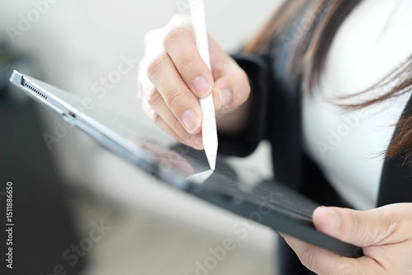 Obraz A person using a digital stylus to write or draw on a tablet device, focusing on technology and creativity.