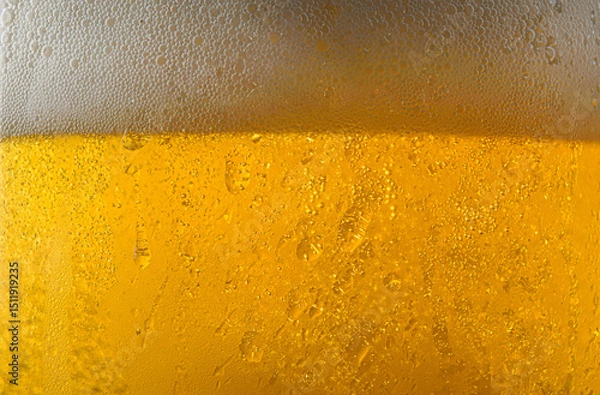 Fototapeta Macro of beer surface and foam in glass with drops