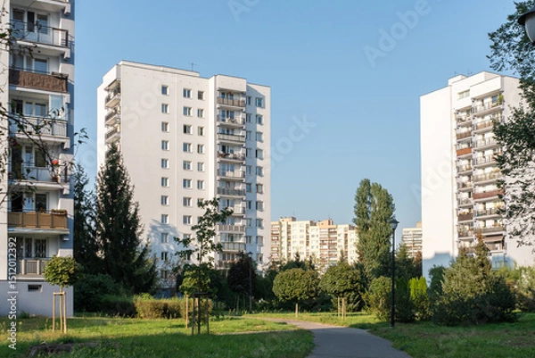 Fototapeta A typical residential housing estate in a city dormitory district. The high-rise blocks of flats are surrounded by a large green park area with trees and a walking path.