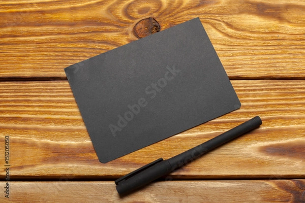 Fototapeta Mockup of black paper on wooden table