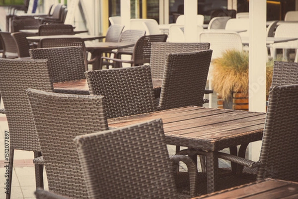 Obraz Chairs made of wicker or rattan and tables on restaurant terrace. Relaxation time on fresh air