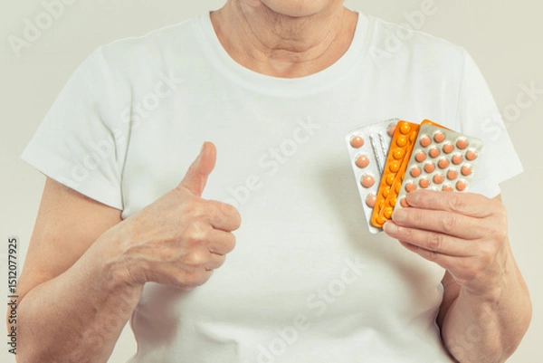 Obraz Elderly senior woman with tablets or supplements in hand. Treatment or strengthening immunity in old age